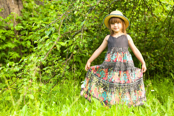 Pieni ihana tyttö poseeraa olkihattu puistossa
 - Valokuva, kuva