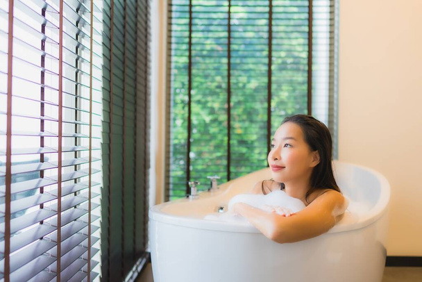 Ritratto bella giovane donna asiatica felice sorriso relax fare un bagno in vasca da bagno interno - Foto, immagini