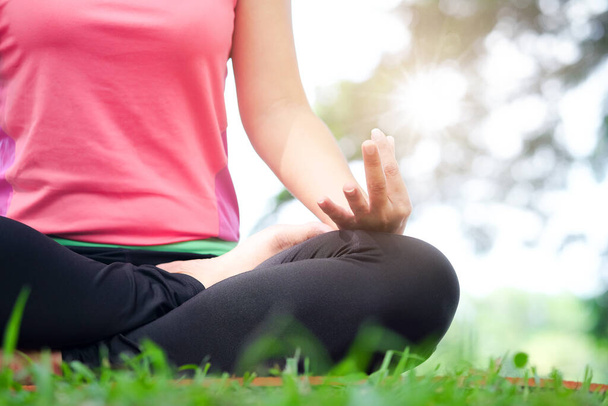 Joga kobieta medytująca na trawie rano, słoneczny czas, koncepcja zdrowia. - Zdjęcie, obraz