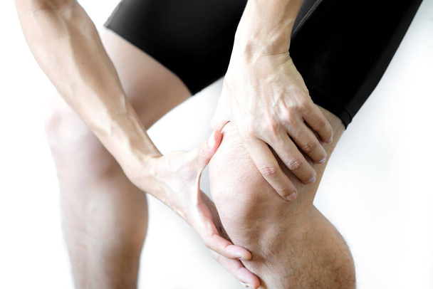 男性アスリートは膝の損傷を持っています,スポーツに苦しんでいる時点で膝の上に彼の手.ホワイト背景健康と医療の概念 - 写真・画像