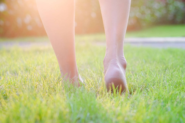 女の足が地面にある。彼女は午前中に運動するために草を歩こうとしている。健康とリラクゼーションの概念 - 写真・画像