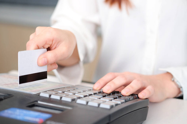 クレジットカードを持っている女性の手彼女はレストランで請求書を支払うためにクレジットカード機械を使用しています。 - 写真・画像