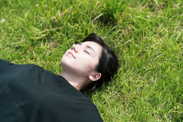 Mujer joven relajándose en el prado en un día soleado
 - Foto, imagen
