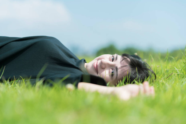 Jovem mulher relaxando no prado em um dia ensolarado
 - Foto, Imagem