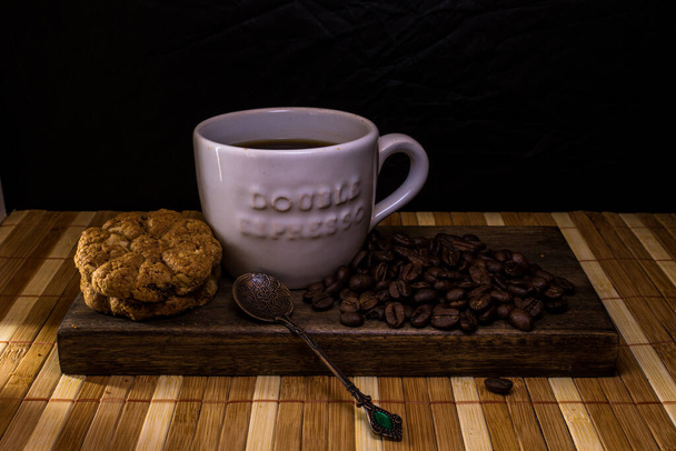 Taza blanca de café en bandeja de madera con galletas y granos de café
 - Foto, Imagen