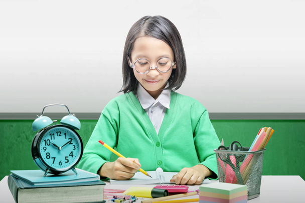 Aziatisch klein meisje met stationair schrijft in het boek op tafel. Terug naar School concept - Foto, afbeelding
