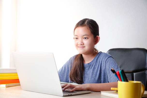 Азійські дівчата навчаються в Інтернеті з дому за допомогою відеодзвінка за допомогою ноутбука, щоб спілкуватися з вчителями. Освітня концепція, соціальна дистанція для зменшення поширення коронавірусу (COVID-19)) - Фото, зображення
