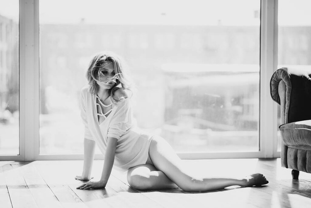 Mulher grávida sexy bonita em uma blusa transparente branca no fundo de uma janela na luz de fundo. Foto em preto e branco. Bela arte. Expectativa de uma criança. Foco seletivo suave
. - Foto, Imagem