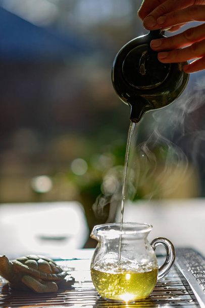 Chinesische Teezeremonie. Keramische Teekanne und Tassen mit dem berühmten chinesischen Puertee mit Dampf. Weicher Fokus. - Foto, Bild