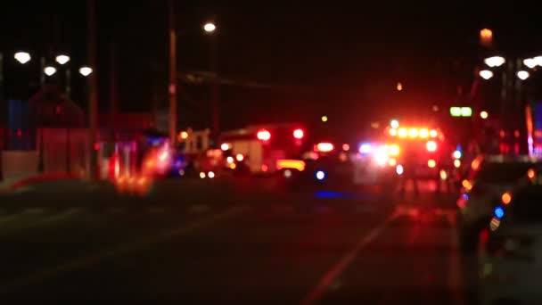 Luci di scena sfocate lampeggianti camion dei pompieri e auto della polizia persone in piedi in strada - Filmati, video