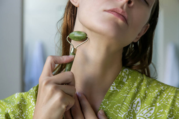 Gezichtsmassage. Vrouw met jade face roller voor huidverzorging. - Foto, afbeelding