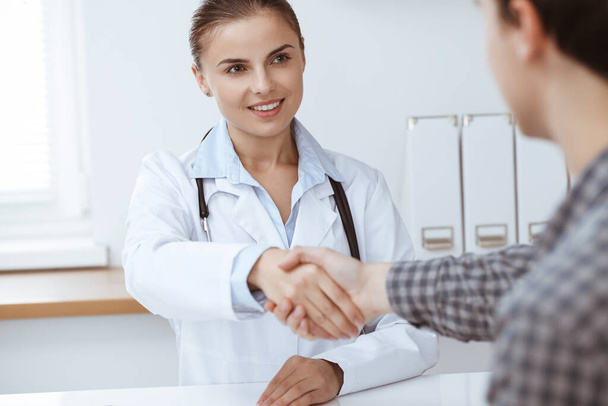 Woman-doctor smiling while shaking hands with her male patient. Medicine concept - Foto, immagini