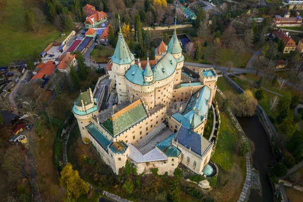 Schloss Bojnice aus der Vogelperspektive, umgeben von Wassergraben, Grünanlagen und städtischen Gebäuden. - Foto, Bild