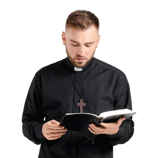 Handsome young priest with Bible on white background - Photo, Image