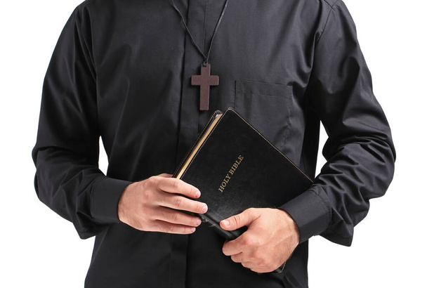 Jóképű fiatal pap Biblia fehér háttér, közelkép - Fotó, kép