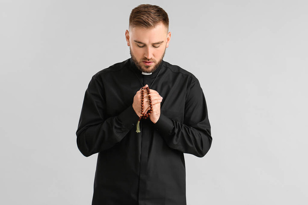 Nuori pappi rukoilee Jumalaa valoisalla taustalla - Valokuva, kuva
