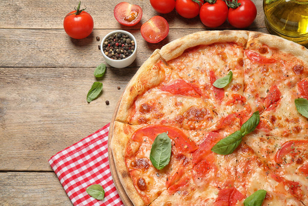 Delicious pizza Margherita and ingredients on wooden table, flat lay - Photo, image