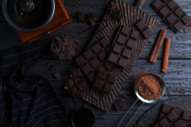 Flat lay composition with dark chocolate on black wooden table - Foto, afbeelding
