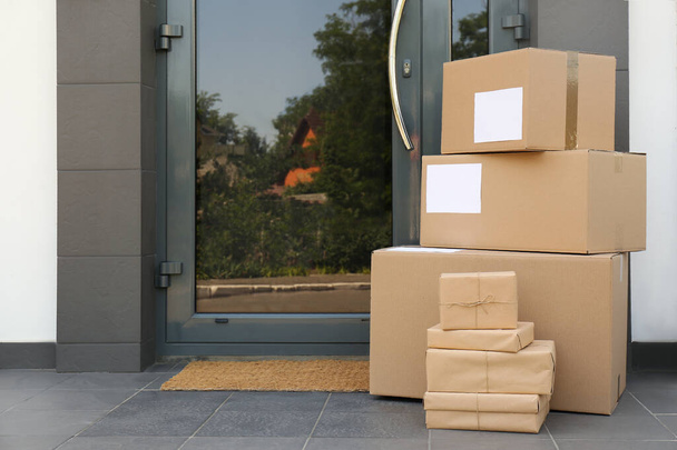Cardboard boxes near door. Parcel delivery service - Foto, afbeelding