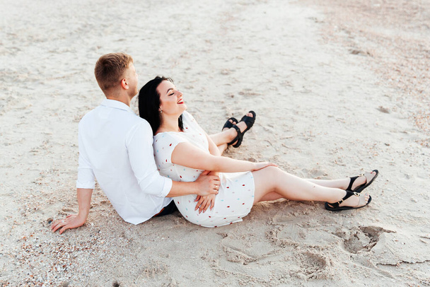Loving couple in white clothes during a honeymoon at sea walk on the sand at a photoshoot Love Story, ocean coast, beach - Foto, Imagen