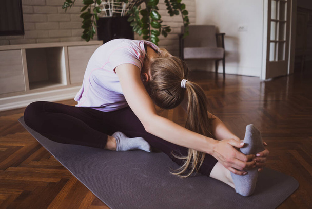 Mujer joven practicando pilates y ejercicios de yoga en casa
. - Foto, Imagen