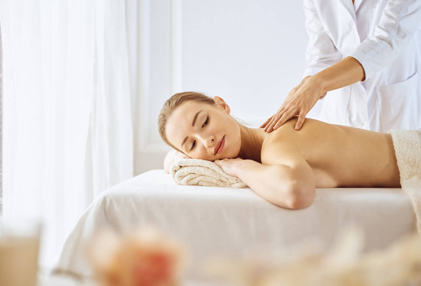 Beautiful woman enjoying back massage with closed eyes. Spa treatment concept - Foto, Imagem