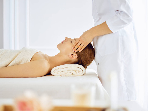 Beautiful woman enjoying facial massage with closed eyes. Spa treatment concept in medicine - Photo, Image