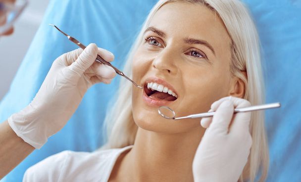 Smiling blonde woman examined by dentist at dental clinic. Healthy teeth and medicine concept - 写真・画像