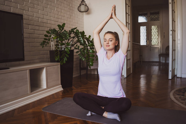 Young woman practicing yoga exercises at home. Padmasana / Lotus Position  - Photo, Image