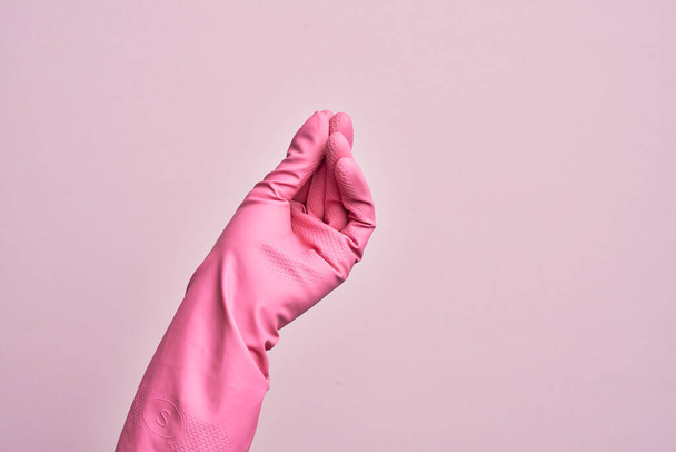 Main de jeune homme caucasien avec gant nettoyant sur fond rose isolé faisant geste italien avec les doigts ensemble, geste de communication mouvement - Photo, image