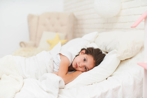 little girl who can't sleep in her crib with her hands under her head, covered with a warm blanket. healthy, long-lasting sleep for children. Problems with falling asleep in the evening. - Valokuva, kuva