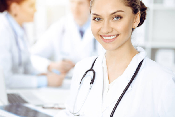 Happy smiling woman-doctor sitting and looking at camera at meeting with medical staff . Medicine concept - Foto, Imagem