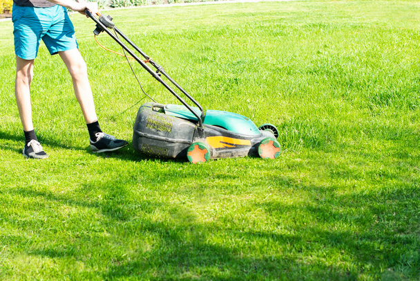 mladý muž seká trávník. Kvalitní fotografie - Fotografie, Obrázek