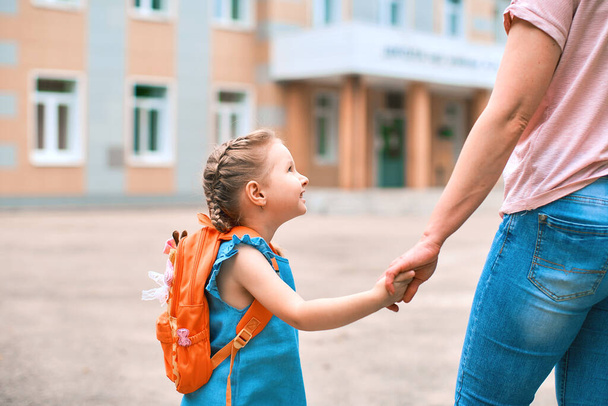 woman morally supports her daughter, holding hands, encourages the child. mother accompanies a student to school. a friendly family goes to kindergarten.happy little girl with a caring mother. - Φωτογραφία, εικόνα