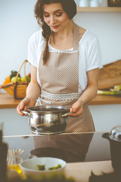 Young brunette woman cooking soup in kitchen. Food and health concept - Foto, Imagem
