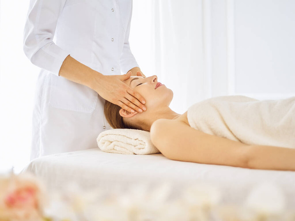Beautiful woman enjoying facial massage with closed eyes - Fotoğraf, Görsel