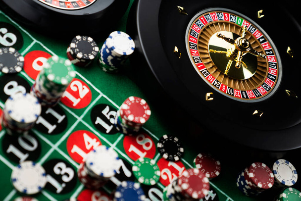 Таблица рулетки в казино. Казино казалось зеленым столом с красными и черными номерами. Стек фишек для покера
. - Фото, изображение