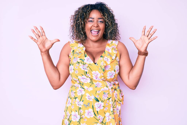 Young african american plus size woman wearing casual clothes celebrating victory with happy smile and winner expression with raised hands  - Фото, зображення