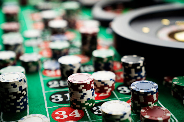 Kumarhanede rulet masası. Kumarhane, üzerinde kırmızı ve siyah sayılar olan yeşil bir masa hissetti. Poker fişleri yığını. - Fotoğraf, Görsel