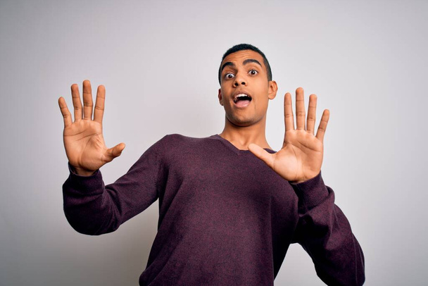 Junge gut aussehende afrikanisch-amerikanische Mann trägt lässigen Pullover über weißem Hintergrund Angst und erschrocken mit Angst Ausdruck Stop-Geste mit den Händen, schreit vor Schreck. Panikkonzept. - Foto, Bild