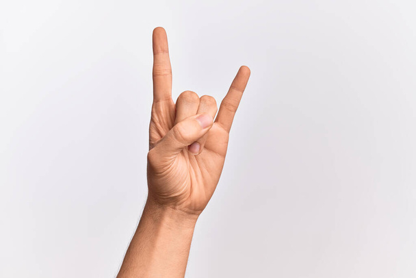 Mano de joven caucásico mostrando los dedos sobre fondo blanco aislado gestos rock and roll símbolo, mostrando cuernos obscenos gesto - Foto, Imagen