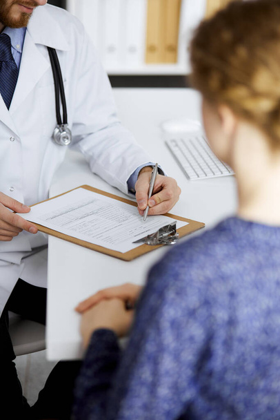 Female doctor and male patient discussing current health examination while sitting in clinic, close-up. Medicine concept - Photo, image