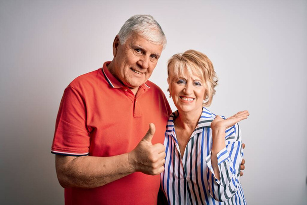 Senior beautiful couple standing together over isolated white background Showing palm hand and doing ok gesture with thumbs up, smiling happy and cheerful - Foto, Imagen