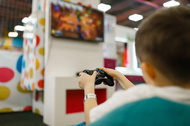Boy joga um console de jogos no centro de entretenimento. masculino criança lazeres no feriados, infância felicidade, feliz crianças
 - Foto, Imagem