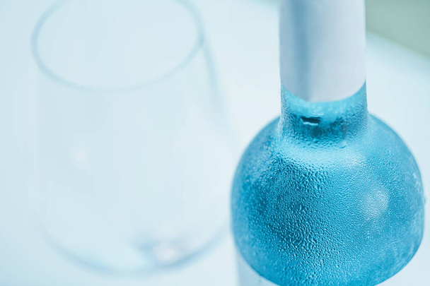Botella de vino azul y copa de vino sobre una mesa
. - Foto, Imagen