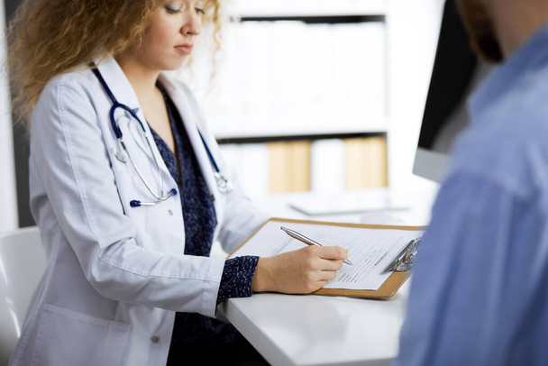 Female doctor and male patient discussing current health examination while sitting in clinic, close-up. Medicine concept - Photo, image
