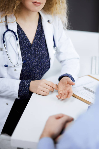 Female doctor and male patient discussing current health examination while sitting in clinic, close-up. Medicine concept - Photo, Image