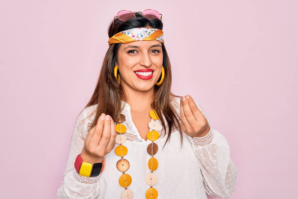 Nuori latino hippi nainen yllään muoti boho tyyli ja aurinkolasit vaaleanpunainen tausta tekee rahaa ele kädet, pyytää palkkaa maksu, miljonääri liiketoimintaa - Valokuva, kuva