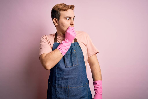 Giovane uomo affascinante redhead cleaner fare lavori di casa indossando grembiule e guanti cercando stressato e nervoso con le mani in bocca mordere le unghie. Problema di ansia. - Foto, immagini