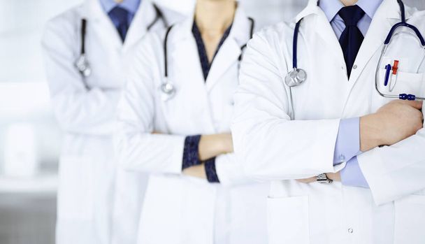 Group of modern doctors standing as a team with crossed arms and stethoscopes in hospital office. Physicians ready to examine and help patients. Medical help, insurance in health care, best desease - Φωτογραφία, εικόνα